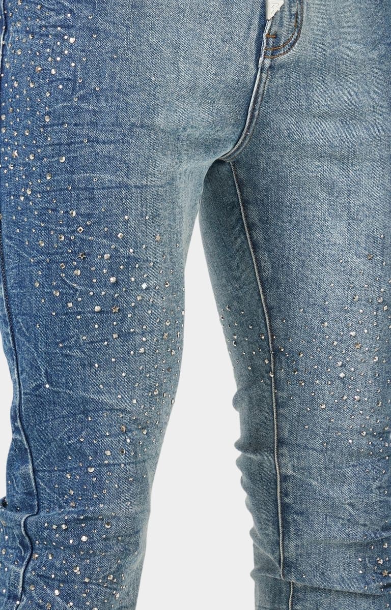 Close-up Rhinestones:
Sparkling rhinestone embellishments on blue stacked skinny jeans.