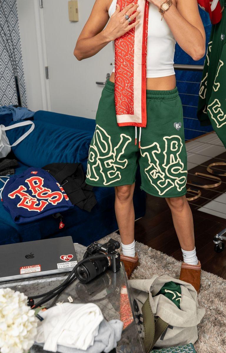 Male model wearing green Red Letters Scattered Sweat Shorts, front view.