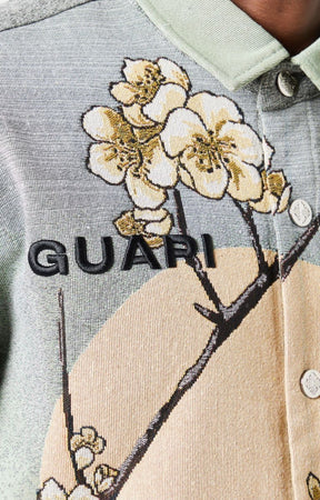Guapi men’s tapestry floral button-down shirt in pastel green with cherry blossom design, modeled against white background