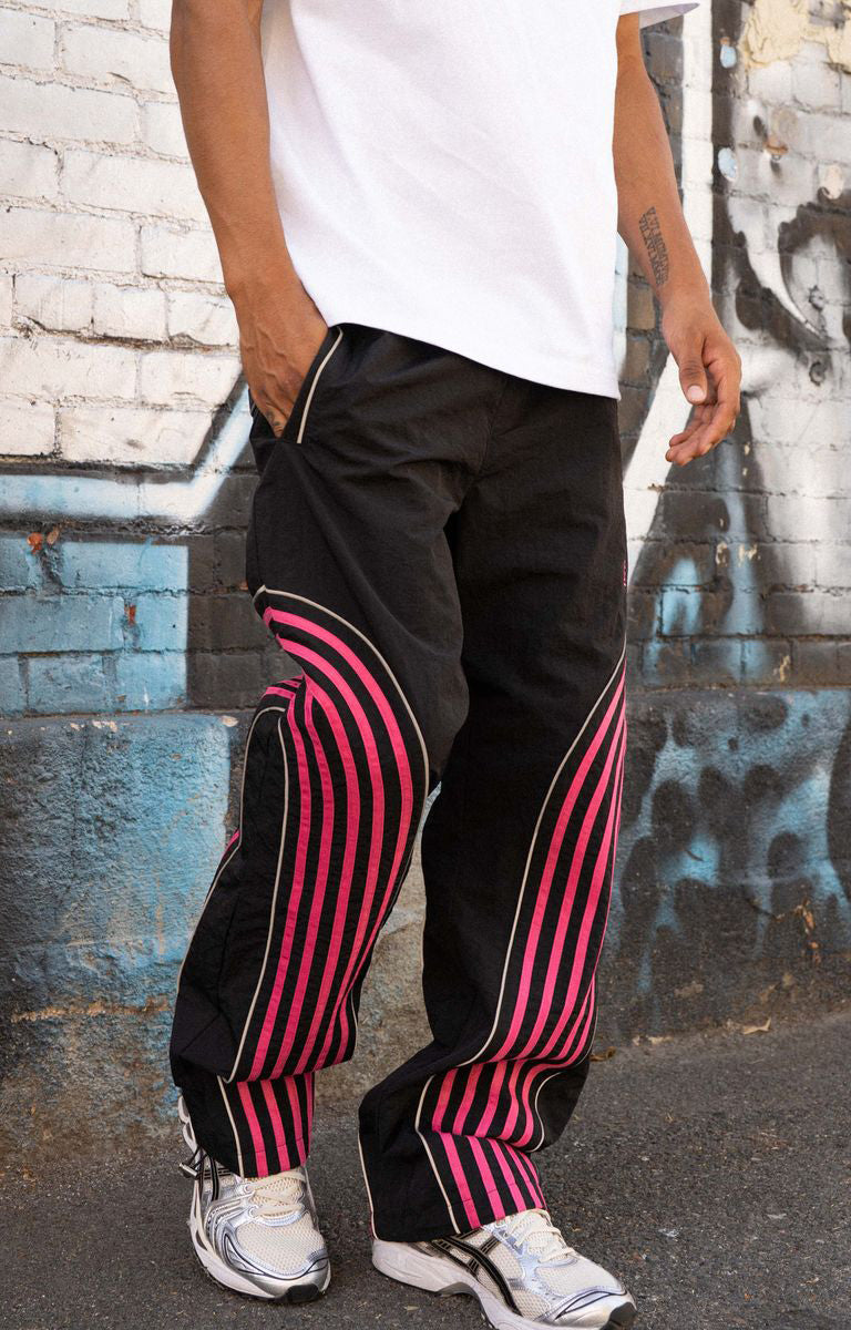 Shop EPTM Flasher Pants in Black, featuring bold pink pop-color tape, signature 3M reflective accents and a 100% polyester construction. Designed with an elastic drawstring waistband, front welt pockets, a back pocket and adjustable bottom toggles for versatile streetwear styling.