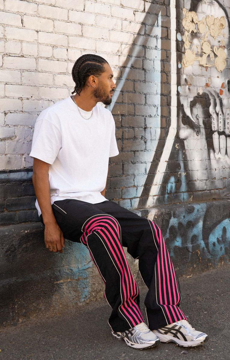 Shop EPTM Flasher Pants in Black, featuring bold pink pop-color tape, signature 3M reflective accents and a 100% polyester construction. Designed with an elastic drawstring waistband, front welt pockets, a back pocket and adjustable bottom toggles for versatile streetwear styling.