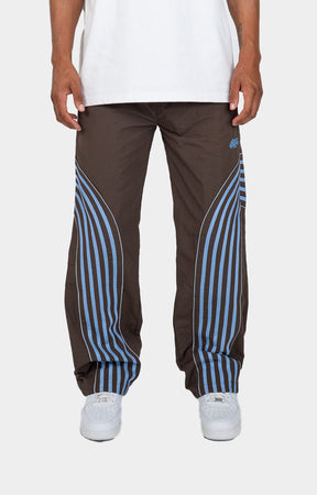 Discover the EPTM Flasher Pants in Brown/Blue, featuring bold pop-color tape and signature 3M reflective accents. Made from 100% polyester, these track pants include an elastic drawstring waistband, front welt pockets, a back pocket, and adjustable bottom toggles. A distinctive streetwear option for styling with graphic tees, hoodies, and sneakers.