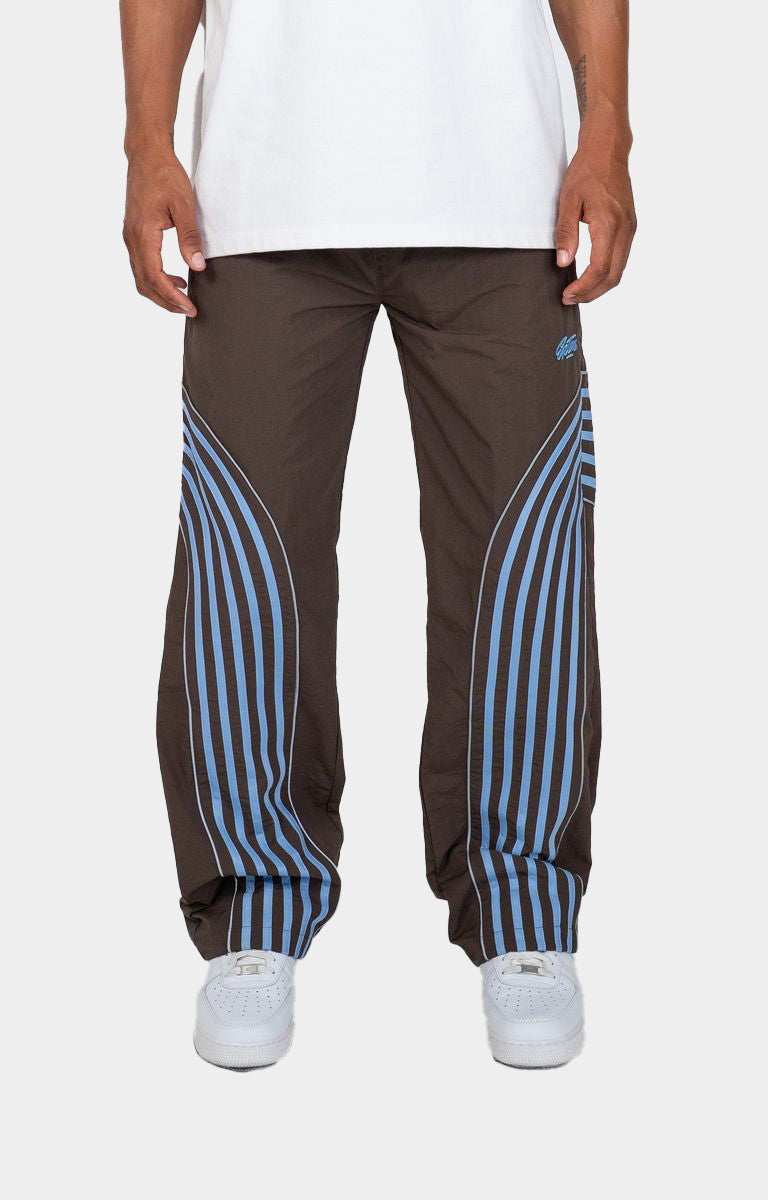 Discover the EPTM Flasher Pants in Brown/Blue, featuring bold pop-color tape and signature 3M reflective accents. Made from 100% polyester, these track pants include an elastic drawstring waistband, front welt pockets, a back pocket, and adjustable bottom toggles. A distinctive streetwear option for styling with graphic tees, hoodies, and sneakers.