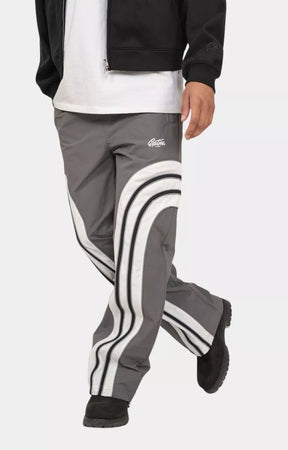 Side view of model wearing grey color block track pants.