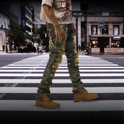 Man wearing Essence premium stacked jeans with print and patches and boots walking across urban crosswalk