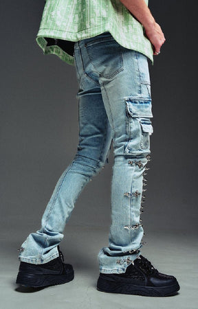 Guapi Aqua wash blue denim cargo pants with ripped details, metal studs, and frayed edges, shown on a model wearing black platform sneakers.