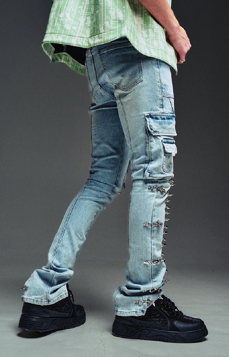 Guapi Aqua wash blue denim cargo pants with ripped details, metal studs, and frayed edges, shown on a model wearing black platform sneakers.