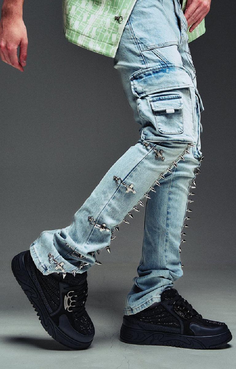 Guapi Aqua Blue wash blue denim cargo pants with silver metal spikes and cross embellishments, shown on a model wearing black platform sneakers. 