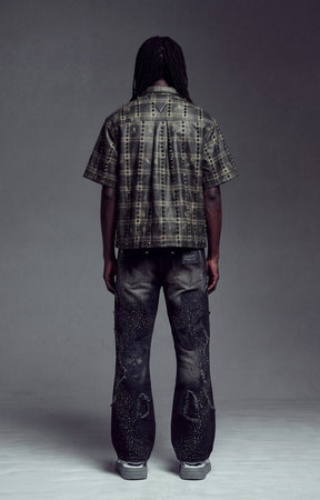 Back View of Guapi Obsidian Black No Hugs Shirt, a short-sleeve plaid button-up shirt and heavily distressed black jeans.