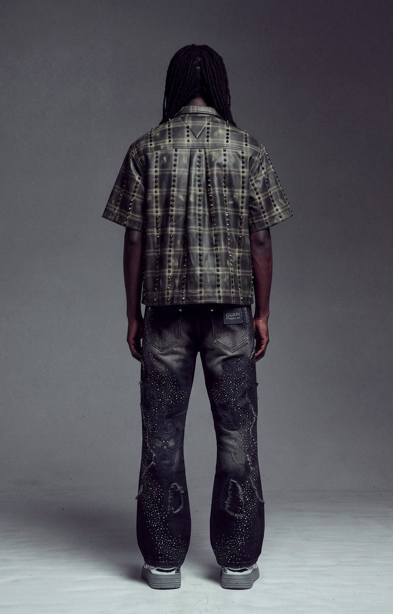 Back View of Guapi Obsidian Black No Hugs Shirt, a short-sleeve plaid button-up shirt and heavily distressed black jeans.