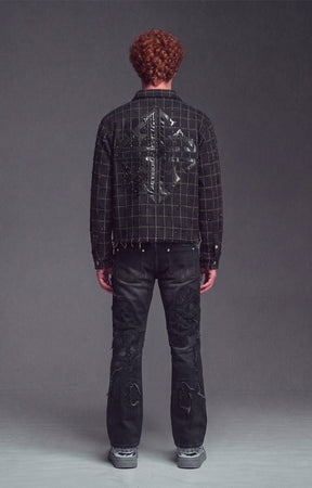 Back view of Guapi Obsidian Black Grid Shirt - black plaid frayed jacket with a large signature guapi cross motif in leather with embellishments on the back, paired with distressed black jeans and gray sneakers.