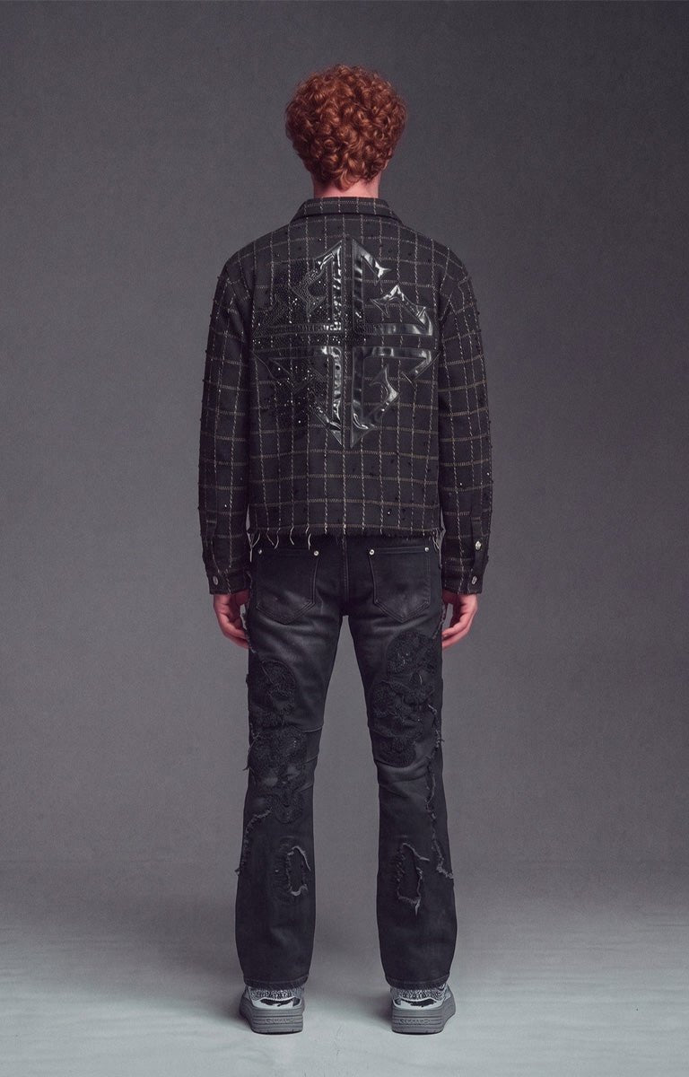 Back view of Guapi Obsidian Black Grid Shirt - black plaid frayed jacket with a large signature guapi cross motif in leather with embellishments on the back, paired with distressed black jeans and gray sneakers.