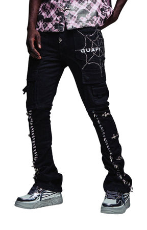 Guapi Obsidian Black cargo pants with silver rhinestone spiderweb details on the thigh, silver rhinestone lace-up straps down the legs, silver spikes on both legs, and 'GUAPI' printed in white on the side, shown on a model.