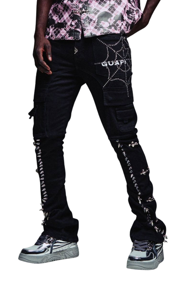 Guapi Obsidian Black cargo pants with silver rhinestone spiderweb details on the thigh, silver rhinestone lace-up straps down the legs, silver spikes on both legs, and 'GUAPI' printed in white on the side, shown on a model.