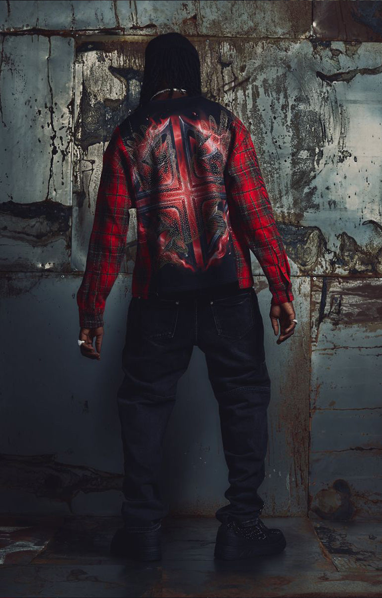 The Guapi Blood Eagle Flannel Tee in Black/Red combines a black graphic tee body with red and black plaid flannel sleeves for a distinctive layered look. Featuring bold eagle, skull, and flame-inspired artwork with decorative embellishments, this relaxed-fit statement top pairs with denim, cargo pants, and alternative streetwear outfits.