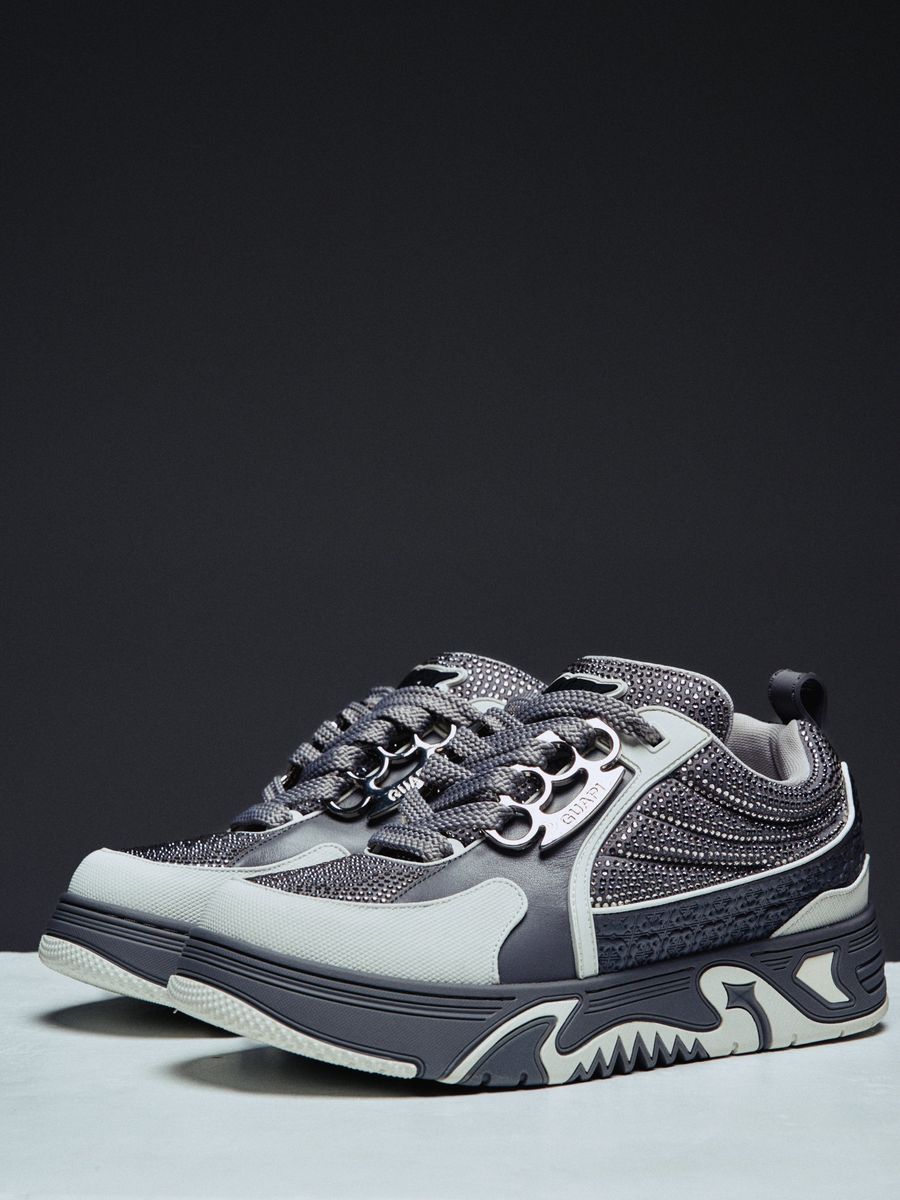 Guapi Cloud Grey Skate Star Sneakers featuring grey and charcoal panels, studded detailing, oversized laces, GUAPI metal hardware, graphic tongue patch, and sculpted sole.