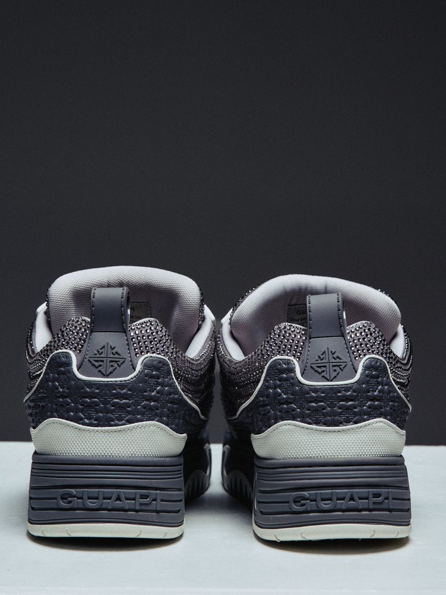 Guapi Cloud Grey Skate Star Sneakers featuring grey and charcoal panels, studded detailing, oversized laces, GUAPI metal hardware, graphic tongue patch, and sculpted sole.