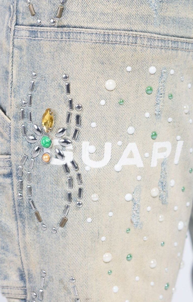 Crystal embellished denim jeans with abstract spider web-inspired artwork.