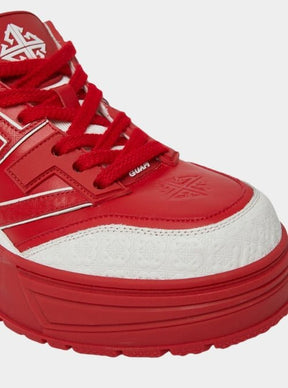 Close-up of embossed GUAPI branding on red sneakers.