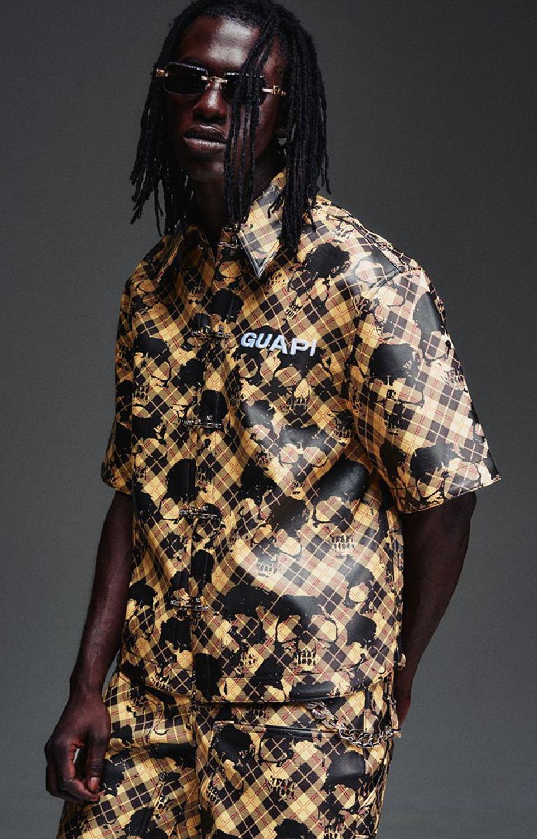 Guapi Gold Skull Plaid Leather Shirt featuring a gold-and-black plaid leather exterior, distressed skull motif, metal toggle closures, chest logo detail and relaxed boxy fit.