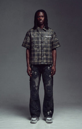 Guapi Obsidian Black No Hugs Shirt. short-sleeve plaid button-up shirt in black and gray, paired with dark distressed jeans featuring white cross motifs and white sneakers.