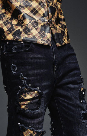 Close-up of GUAPI black denim showing ripped-effect details and plaid fabric inserts.