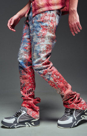 Guapi Red Dust Bandana Denim - distressed, faded red and blue jeans with a red patterned shirt and gray sneakers.
