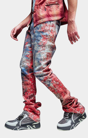 Guapi Red Dust Bandana Denim distressed, faded red and blue jeans with a tie-dye pattern, paired with gray and white sneakers.