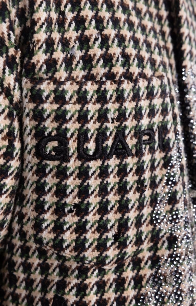 Detailed view of bold embroidery logo on GUAPI shirt jacket.