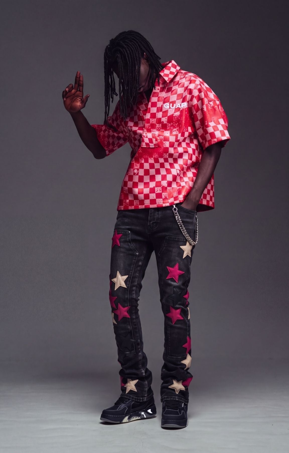 Guapi Wine Red Stars Denim featuring a black denim base, wine red and cream star appliqués, slim tapered fit, and silver-tone chain detail for a bold streetwear look.