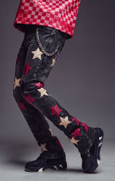 Guapi Wine Red Stars Denim featuring a black denim base, wine red and cream star appliqués, slim tapered fit, and silver-tone chain detail for a bold streetwear look.