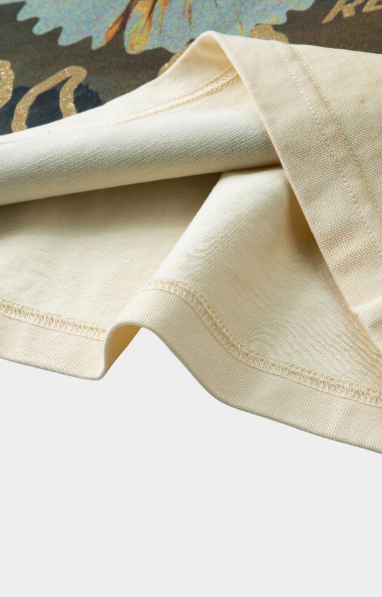 Close-up of Hyde Park Motor Park Tee in beige fabric with visible stitching on a light gray background