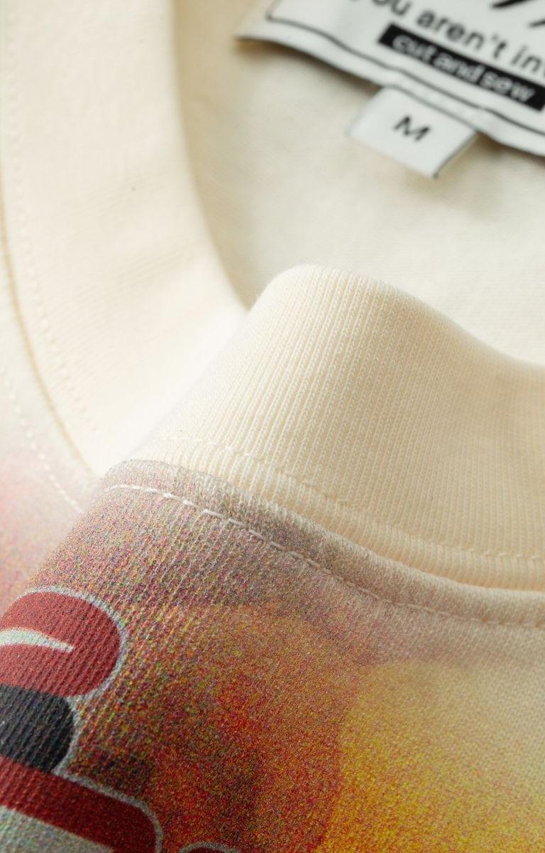 Close-up of a beige sweatshirt with a colorful logo and a tag on the collar.