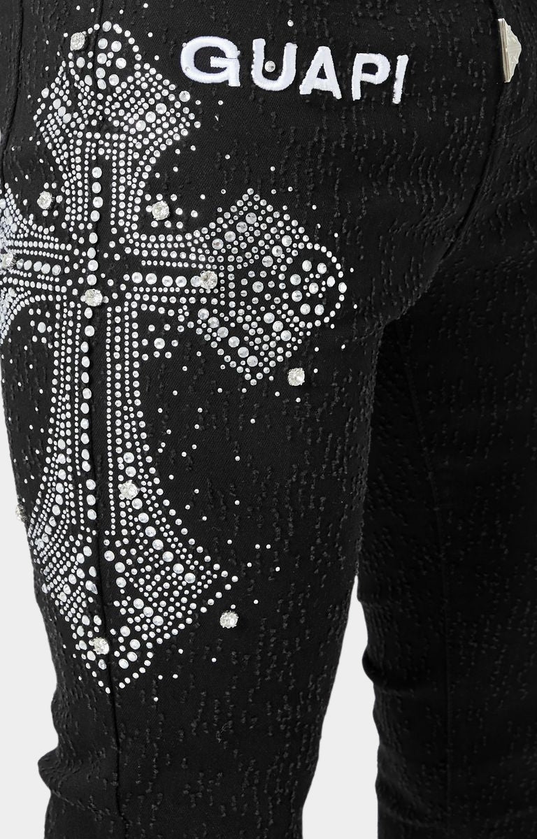 Black skinny jeans with GUAPI branding and detachable silver chain.
