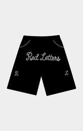 Black shorts featuring 'Red Letters' in white cursive rhinestone lettering across the front, with decorative rhinestone arches near the waistband and matching monogram details on the lower legs. Red Letters Black Pearled French Terry Shorts front view.