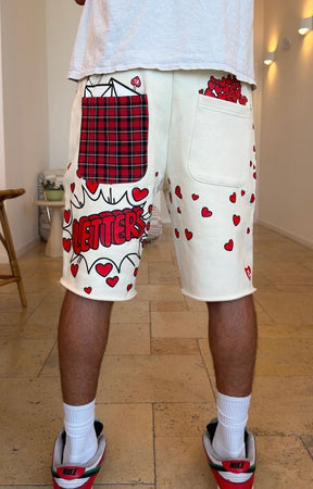 Red Letters off white cream-colored graphic 500 GSM sweat shorts with red hearts, a red plaid pocket, and 'LETTERS' text. 