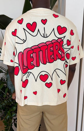 Red Letter cream-colored oversized t-shirt with a red and pink comic-style graphic that reads 'LETTERS' inside a speech bubble, surrounded by small red hearts. 