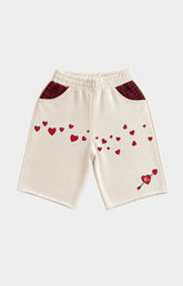 Red Letters Off-white knit shorts with red heart embroidery, red plaid pocket panels, and a small red heart-and-arrow motif near the lower right leg.