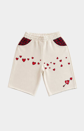 Red Letters Off-white knit shorts with red heart embroidery, red plaid pocket panels, and a small red heart-and-arrow motif near the lower right leg.
