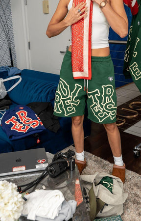 Male model wearing green Red Letters Scattered Sweat Shorts, front view.