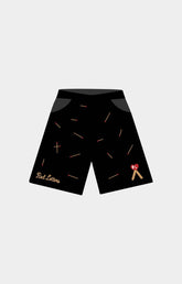 Red Letters Start the Fire 500 GSM Heavyweight French Terry Black athletic shorts with a scattered gold matchsticks pattern, featuring a gold 'Red Letters' script logo on the left leg and a small red and gold ribbon graphic on the right leg. 