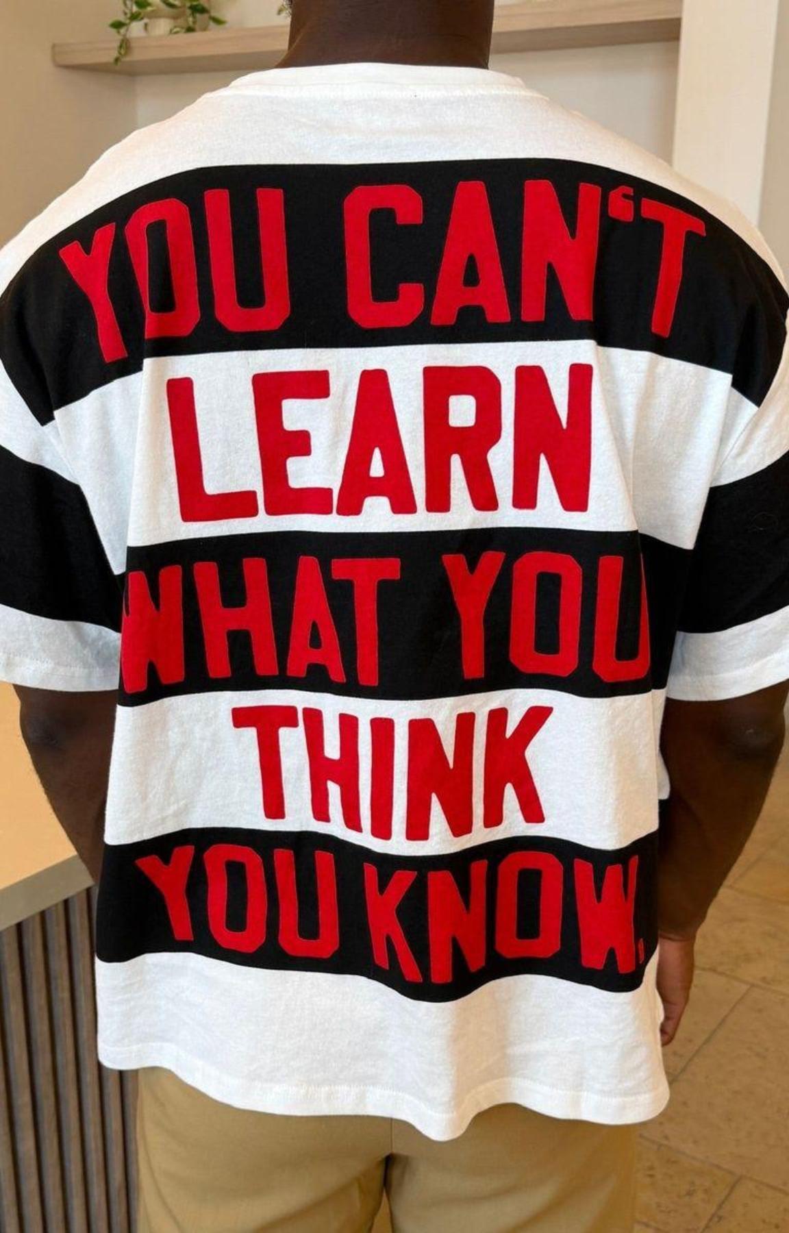 Close-up of Red Letters Unlearn typography graphic on striped tee.