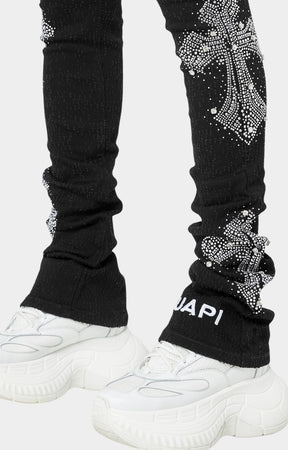 Close-up of black skinny jeans with crystal cross motifs and distressing.