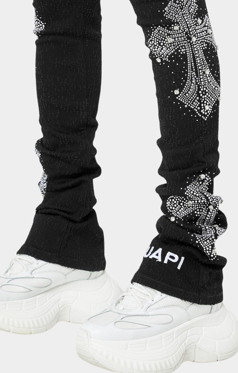 Close-up of black skinny jeans with crystal cross motifs and distressing.