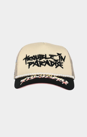 Toxicity Trouble In Paradise trucker hat in cream and black front view.