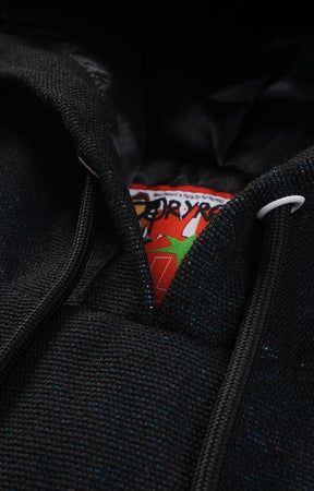 Close-up of a black tapestry hoodie with a brand label showing with drawstrings. 