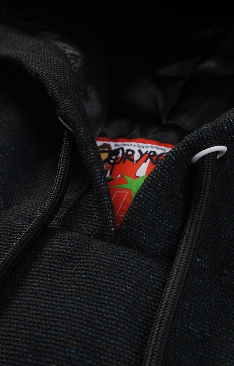 Close-up of a black tapestry hoodie with a brand label showing with drawstrings. 